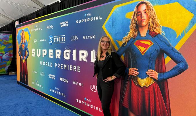 Best Friends CEO Julie Castle in front of a Supergirl world premiere sign